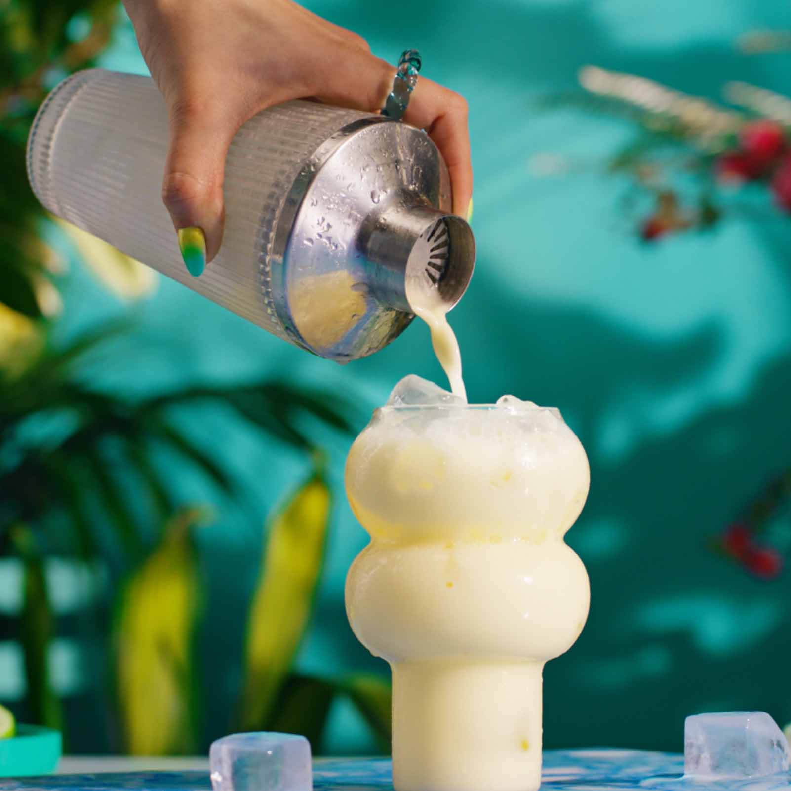 Malibu Pina Colada cocktails being poured from a shaker in a tropical setting - step 5