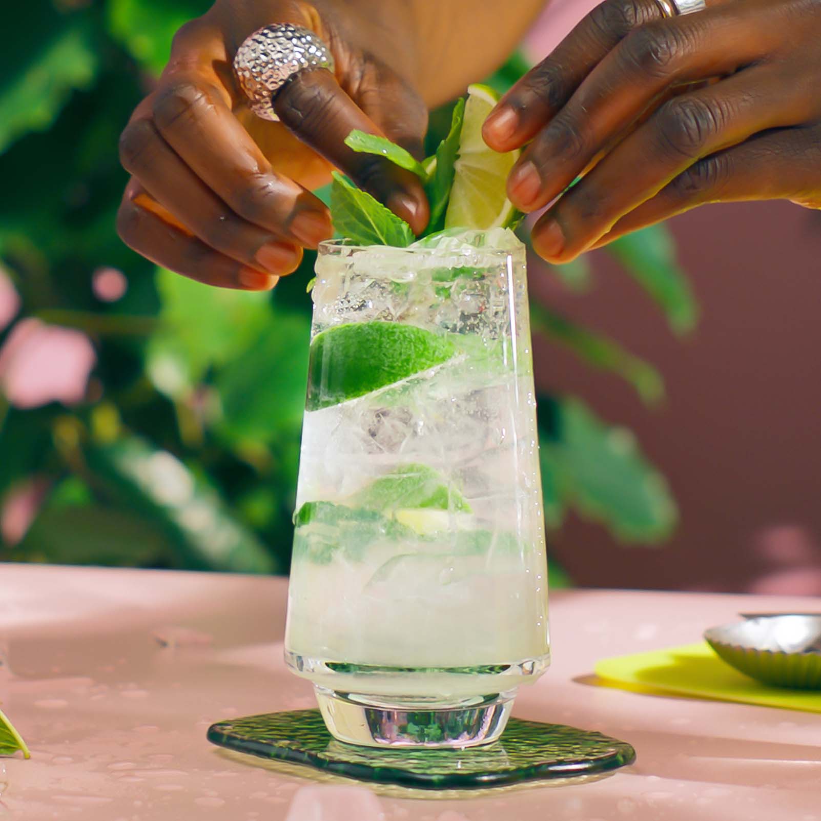 Malibu Mojito on a table in a tropical setting with a garnish of lime and mint being added - step 5