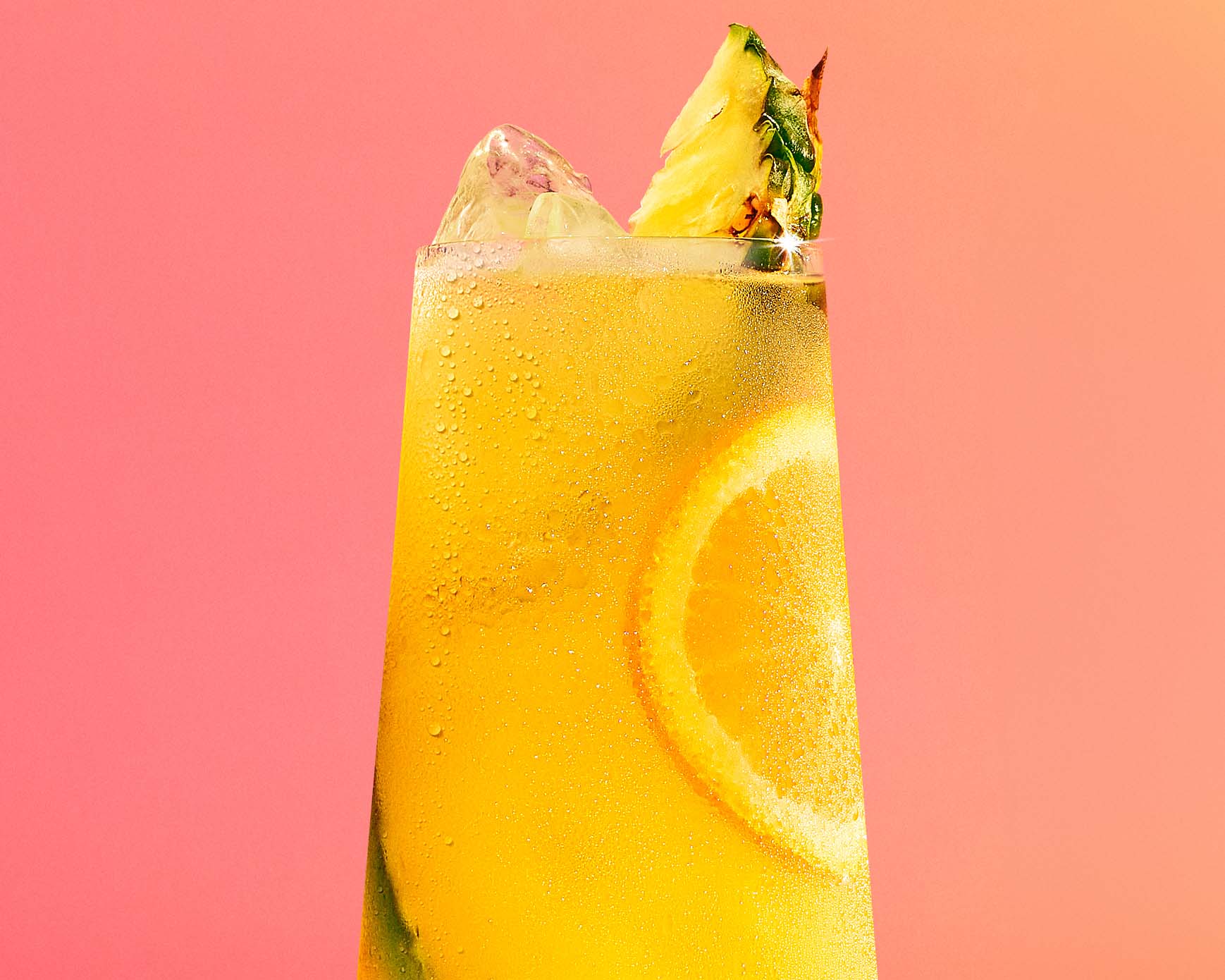 Malibu and pineapple cocktail on a coral background